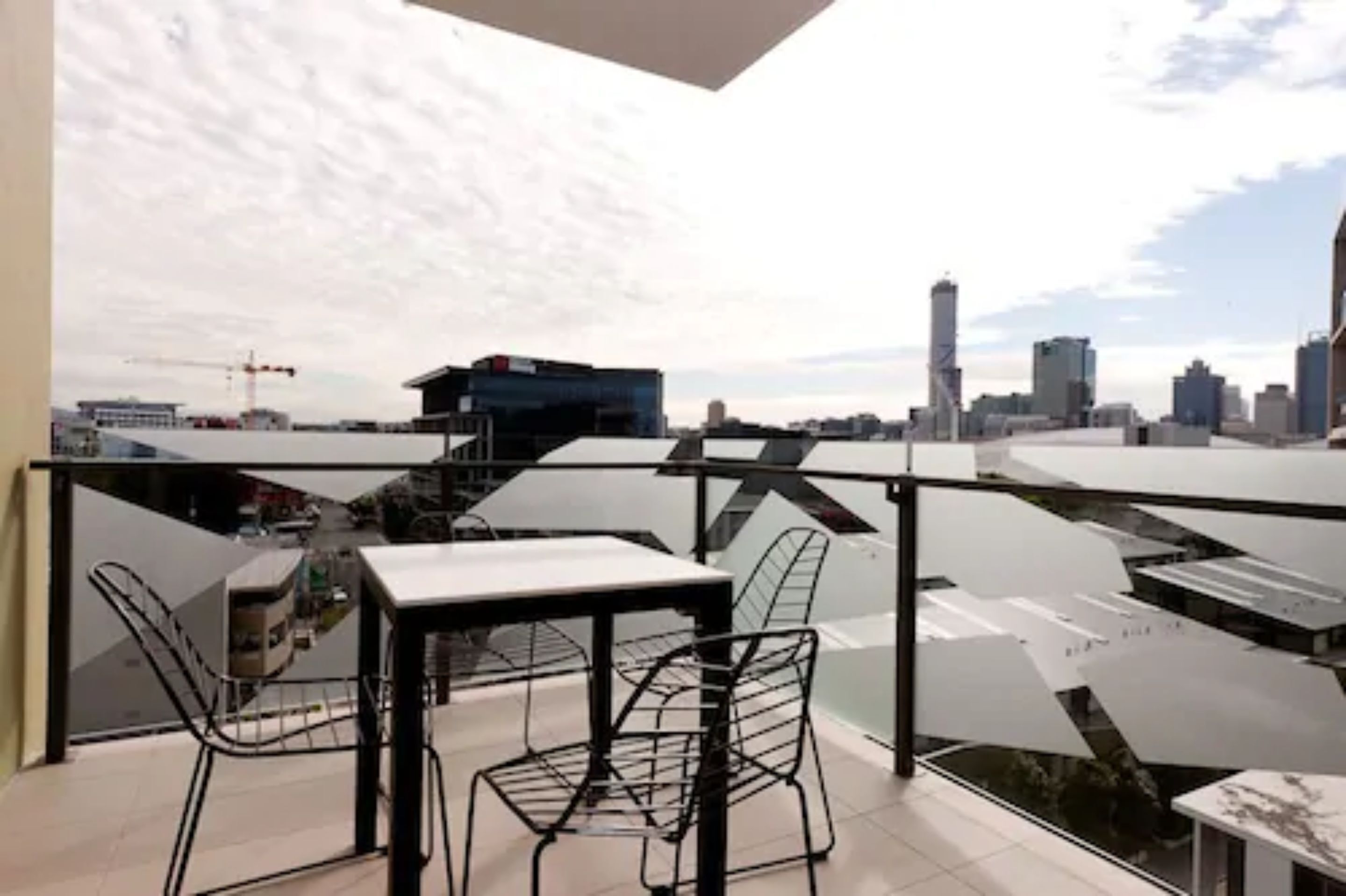Un balcon avec une table et des chaises, offrant une vue sur la ville.