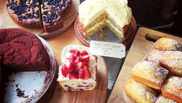 Diversos postres expuestos sobre tablas de madera con etiquetas de precio.
