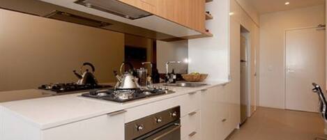 A modern kitchen with white cabinetry, a built-in oven, and a gas stove.