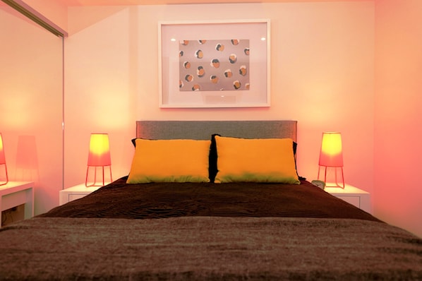 A neatly made bed with two pillows, a headboard, and bedside lamps on either side. - Vine Serviced Apartments (South Brisbane)