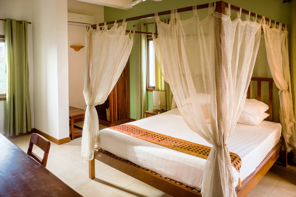 A bed with a canopy, a wooden headboard, and a bedside table with a lamp.