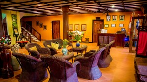 A lobby with wicker furniture, a staircase, and a reception desk. - Robam Inn (Siem Reap)