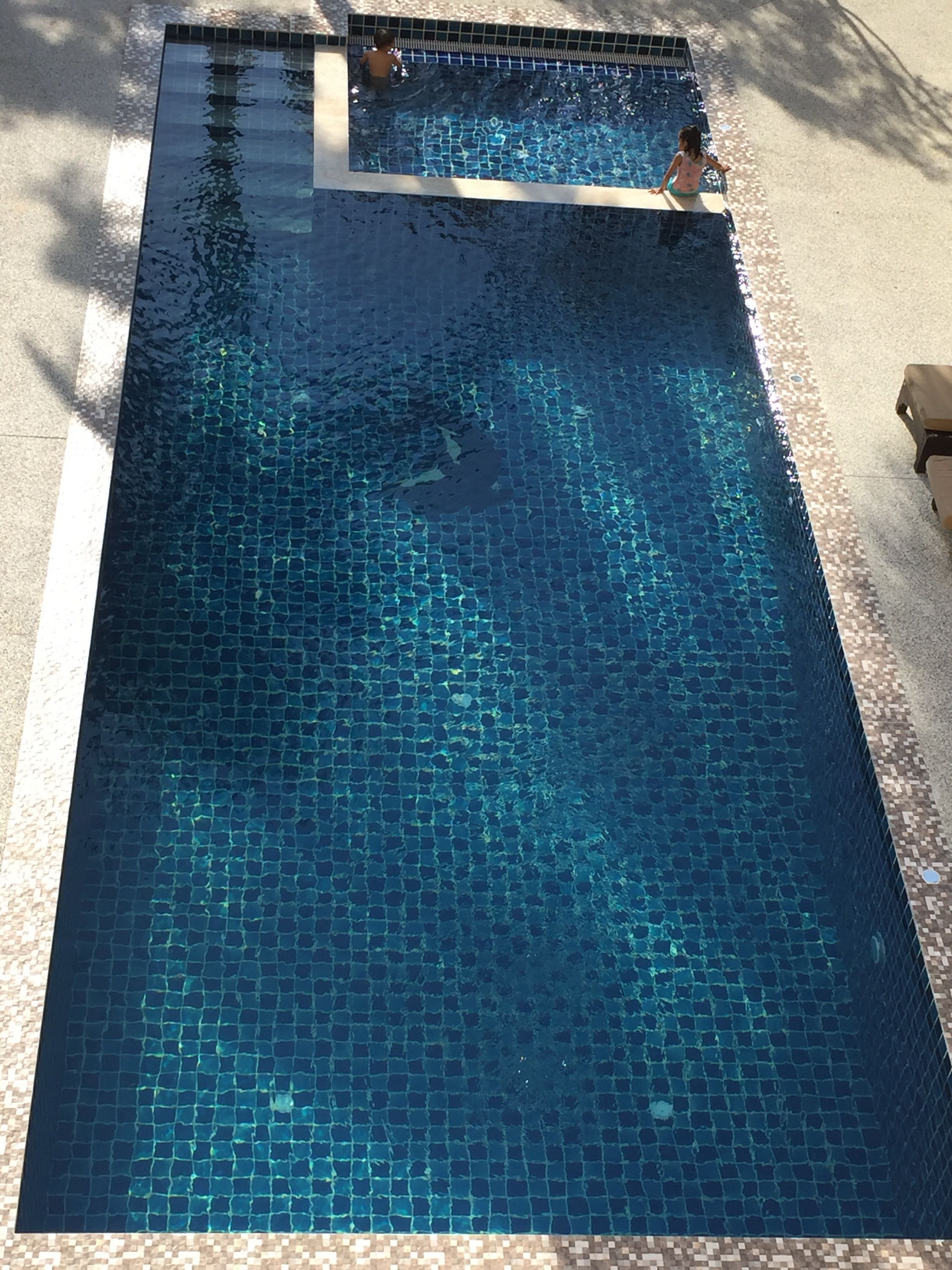 Una piscina rectangular con borde y fondo de azulejos.