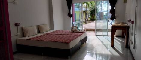 A bedroom with a bed, a small table, and a view of the outside.
