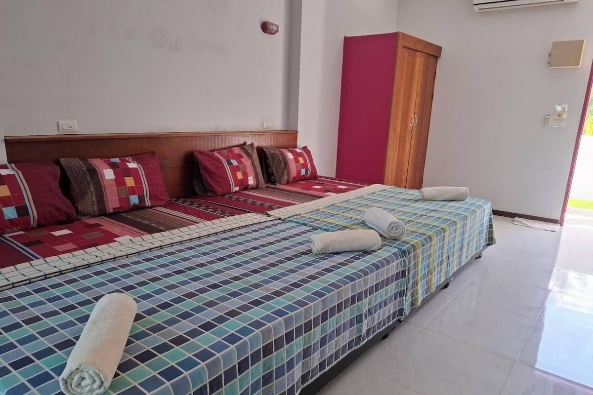 Habitación de hotel con cama, cabecera de madera, armario rojo y equipo de aire acondicionado.