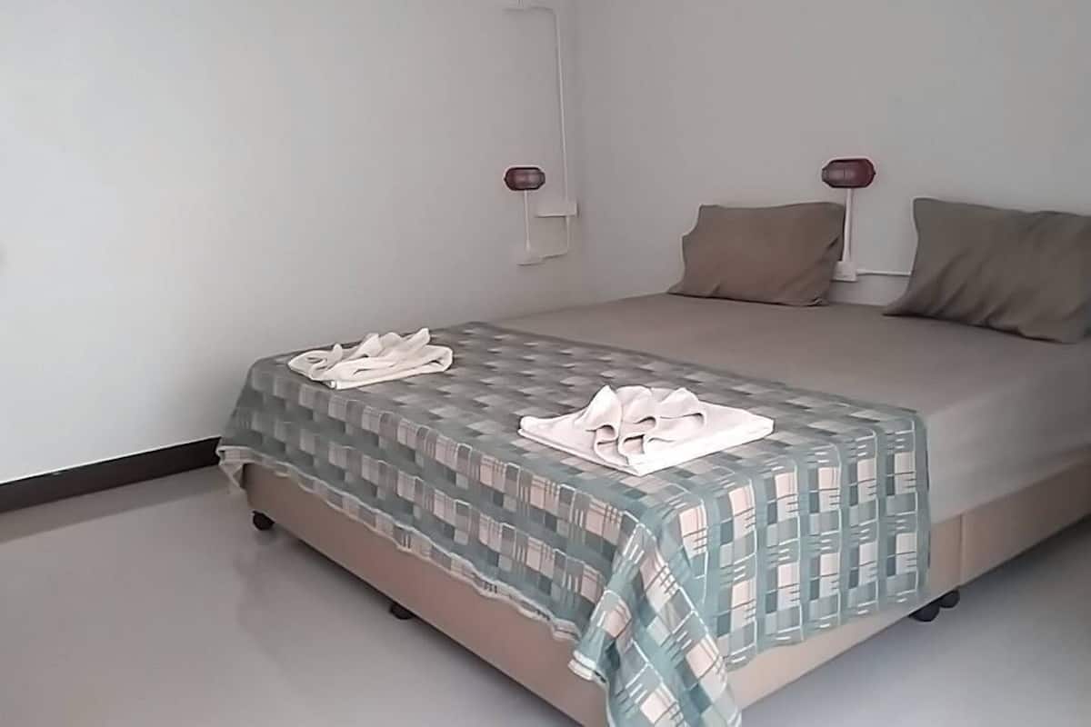 Un dormitorio con cama, almohadas y manta.