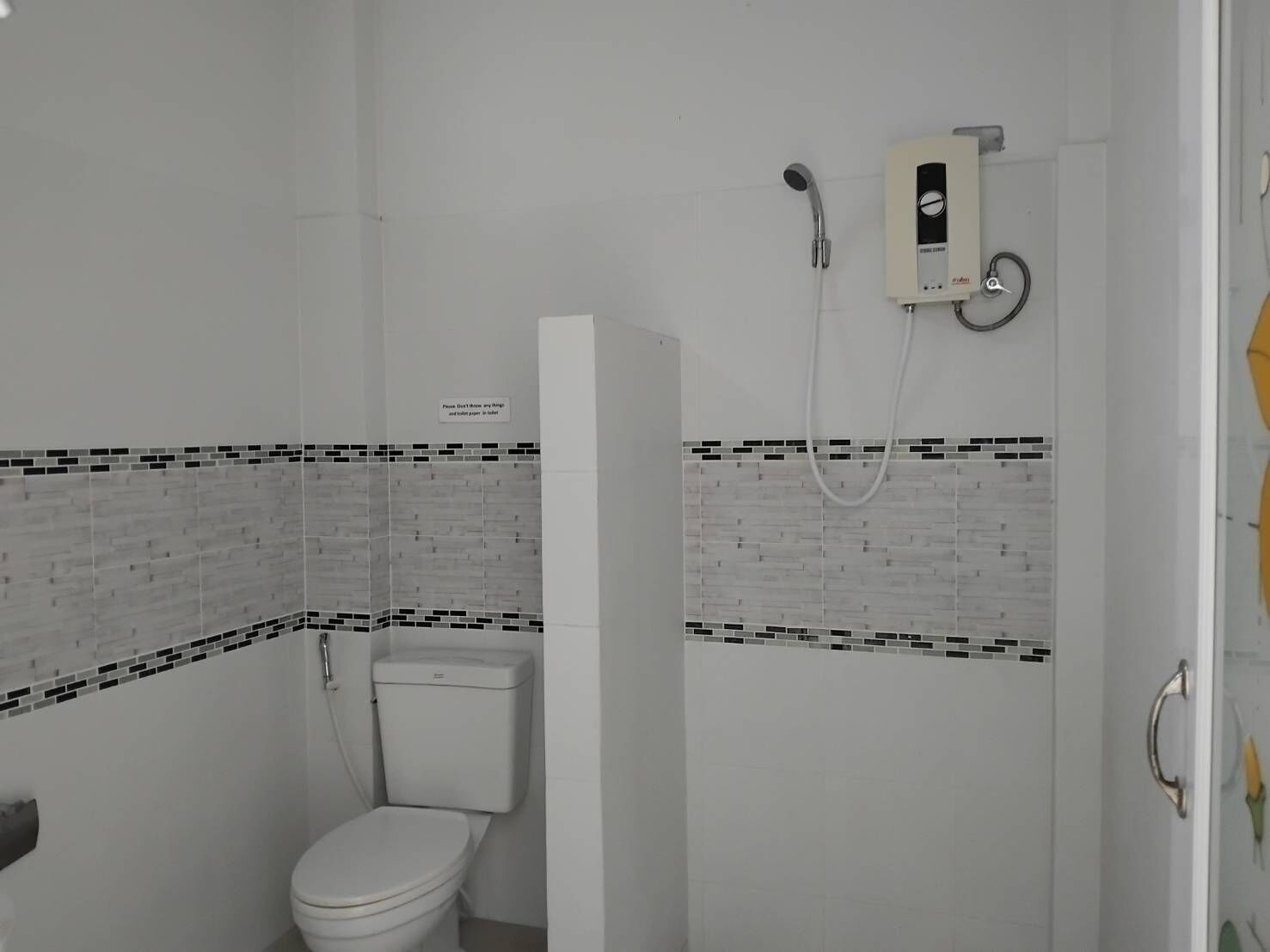 Un baño con inodoro, ducha y un calentador de pared.