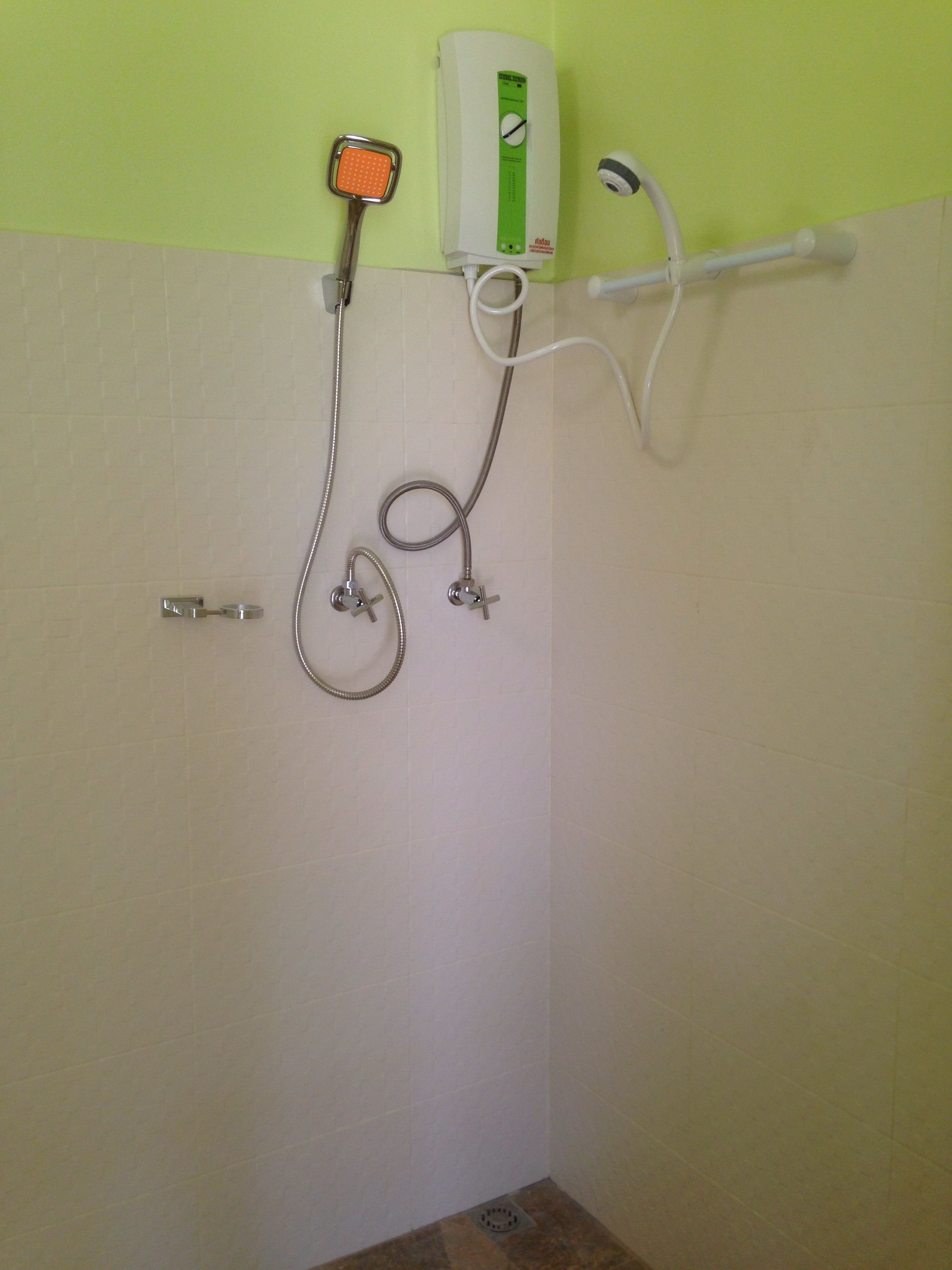 Une douche équipée d’un pommeau de douche à main, d’un panneau de commande mural et d’une brosse à main.