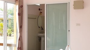 Een hotelkamer met twee bedden, een badkamer en een glazen schuifdeur naar buiten.
