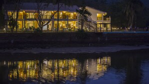 A two-story building with balconies, a staircase, and a reflection in the water.