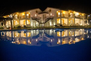Ein mehrstöckiges Hotel mit einer zentralen Treppe, einem Schwimmbad und Außenbereichen zum Sitzen.