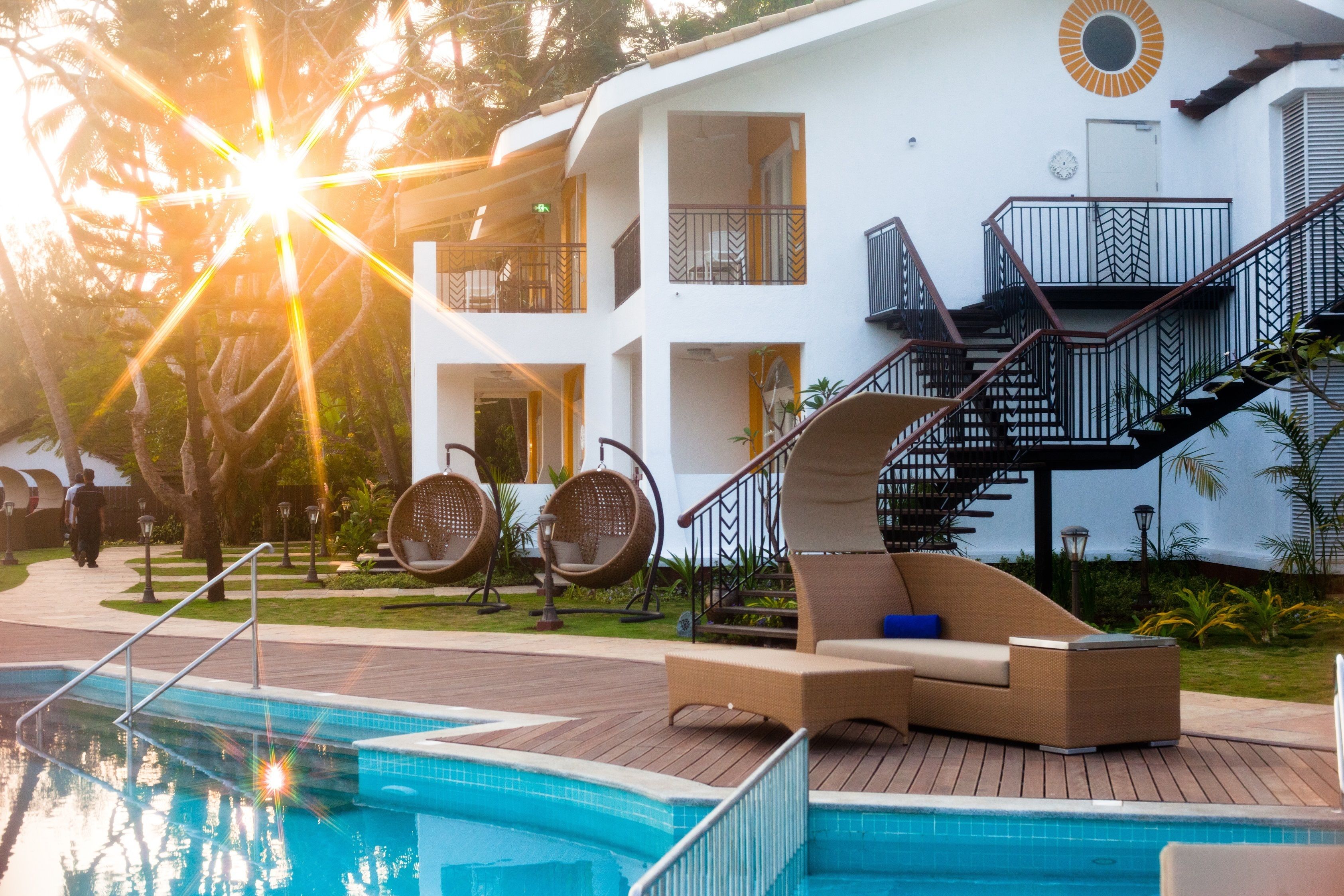 Un área de piscina con sillones reclinables, una escalera y un edificio con balcones.