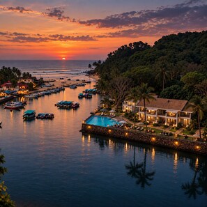 Un resort frente al mar con piscina, barcos y vistas al atardecer.