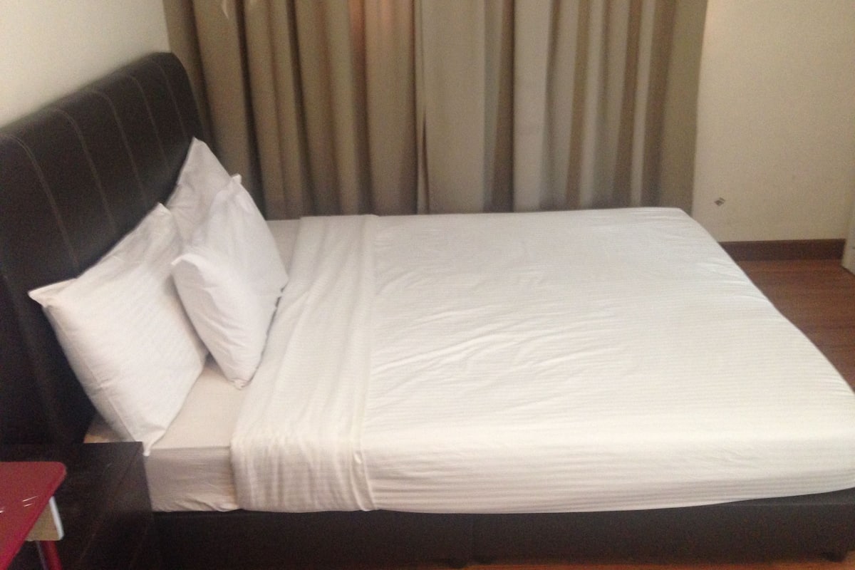 Una cama bien hecha con sábanas blancas en una habitación de hotel.