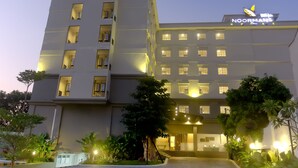 Un hotel de varios pisos con un llamativo letrero de 'Noormans Hotel', con balcones y una entrada bien iluminada.