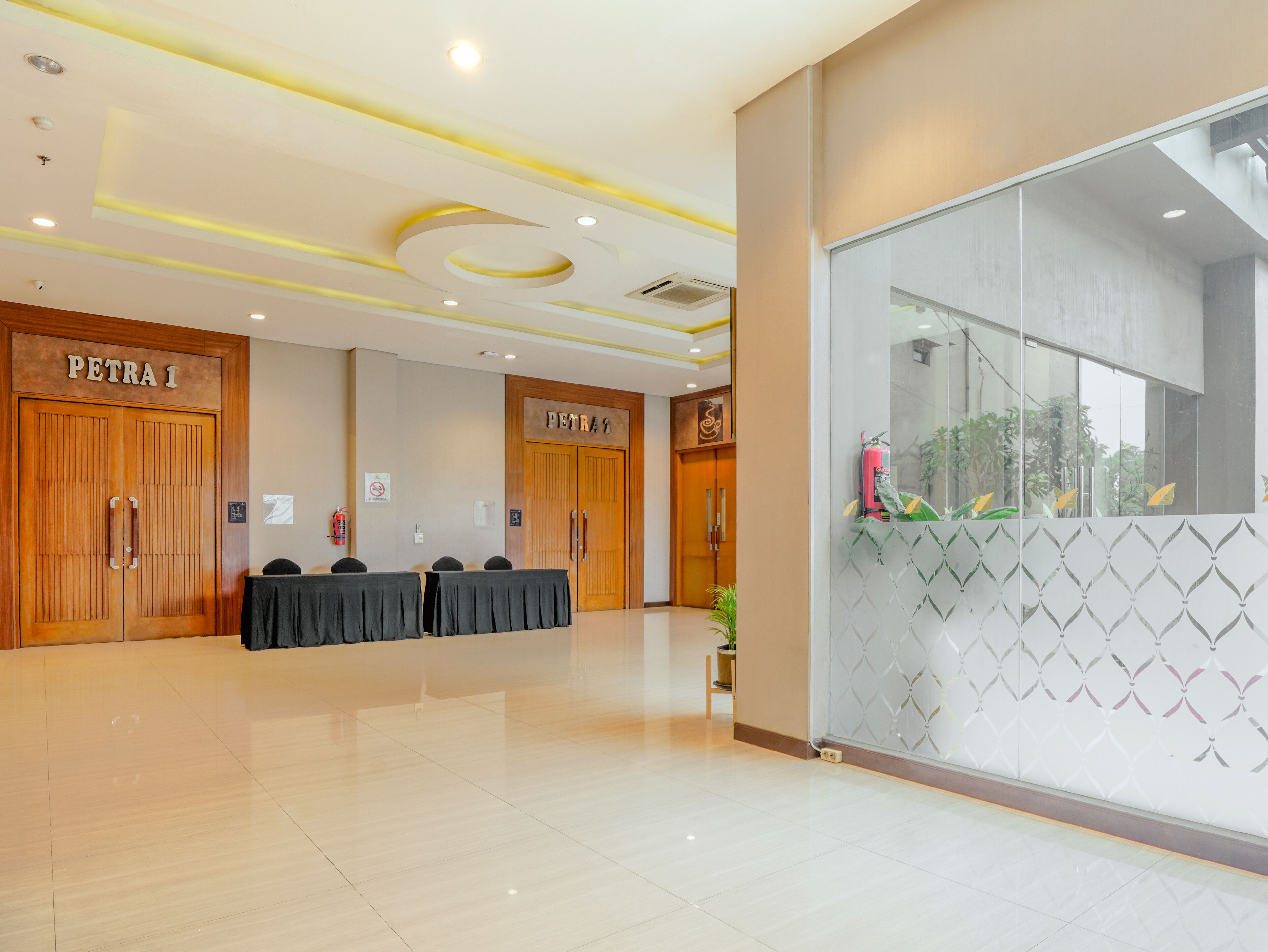 A conference room with two doors labeled 'PETRA 1' and 'PETRA 2', a table with chairs, and a glass wall with a geometric pattern.