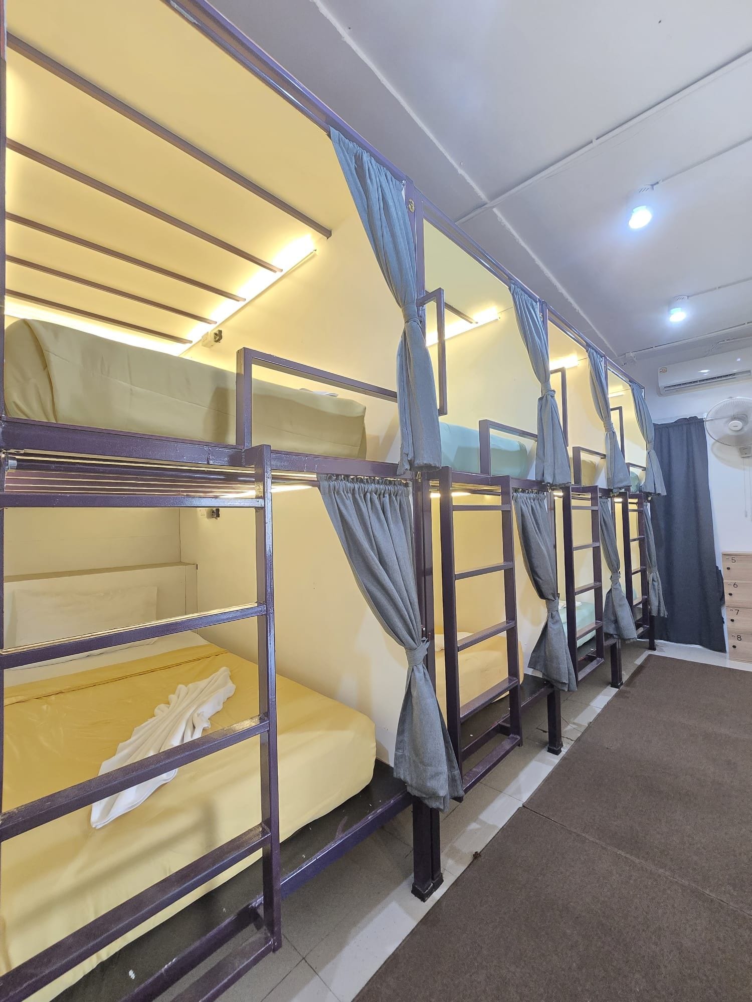 Bunk beds with curtains, a ceiling fan, and a tiled floor.