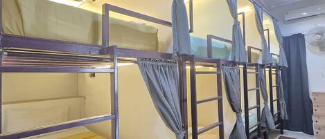 Bunk beds with curtains, a ceiling fan, and a tiled floor.