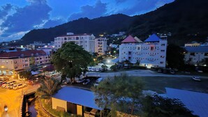 A cityscape with buildings, a parking lot, and a mountain in the background. - Hotel The Journey Patong New (Patong)