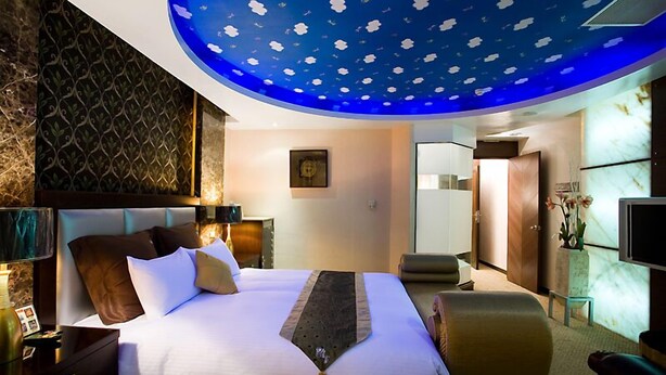 A modern hotel room with a large bed, a desk, and a seating area. - Crystal Motel (Hsinchu)