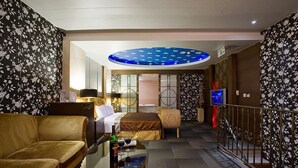 A hotel room with a sofa, a bed, a small table with a bottle and glasses, and a TV. - Crystal Motel (Hsinchu)