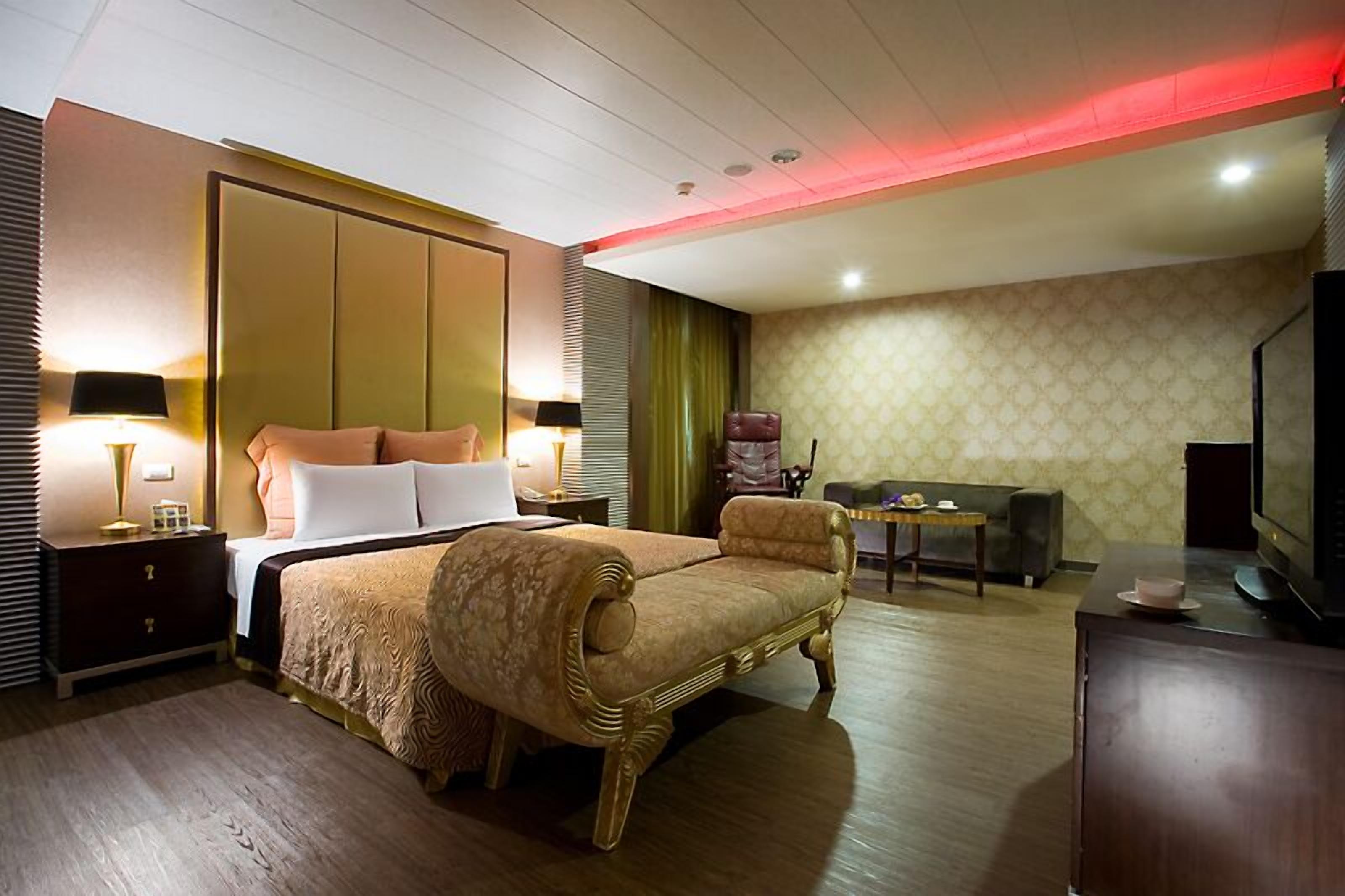A hotel room with a large bed, a sofa, a television, and a desk.