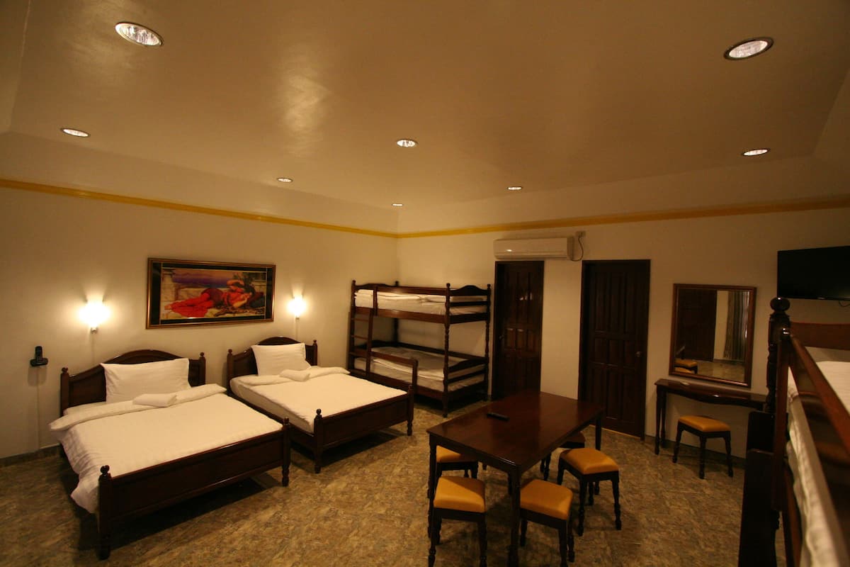 Ein Hotelzimmer mit zwei Einzelbetten, einem Schreibtisch mit Stuhl, einem kleinen Tisch und einem Spiegel.