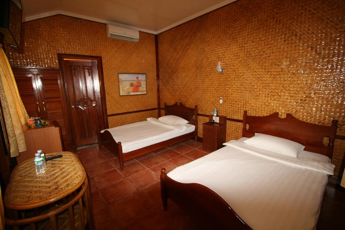Ein Hotelzimmer mit zwei hölzernen Betten, einem kleinen runden Tisch und einem Holzschrank.