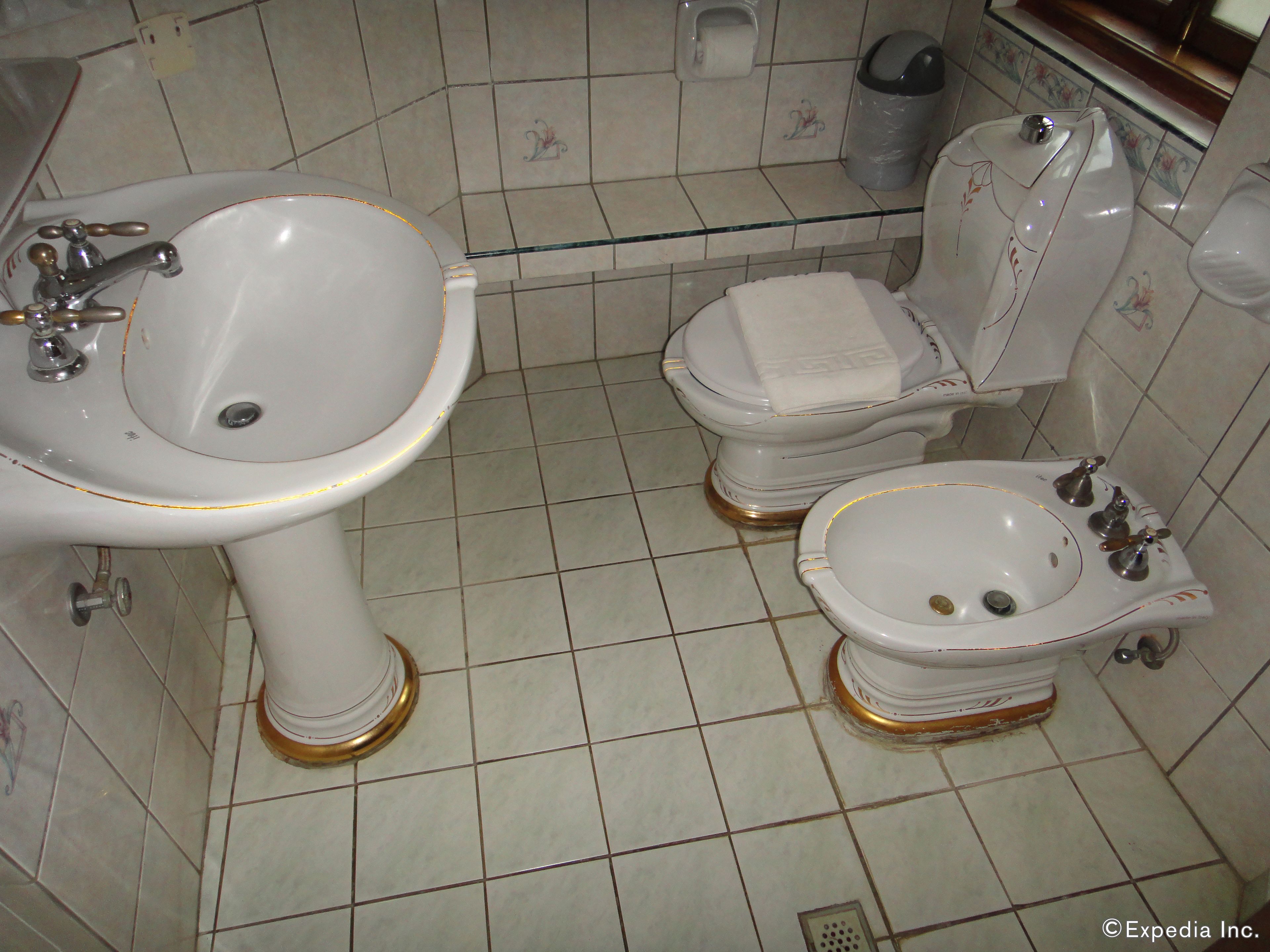 Une salle de bain avec un lavabo sur colonne, des toilettes et un bidet.