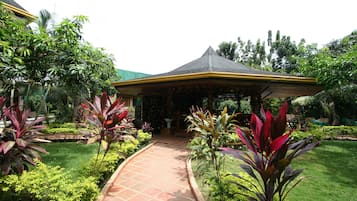 A covered outdoor area with a tiled pathway leading to a building.