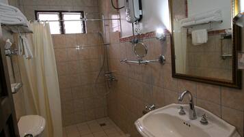 Un baño con inodoro, lavamanos, ducha y espejo.