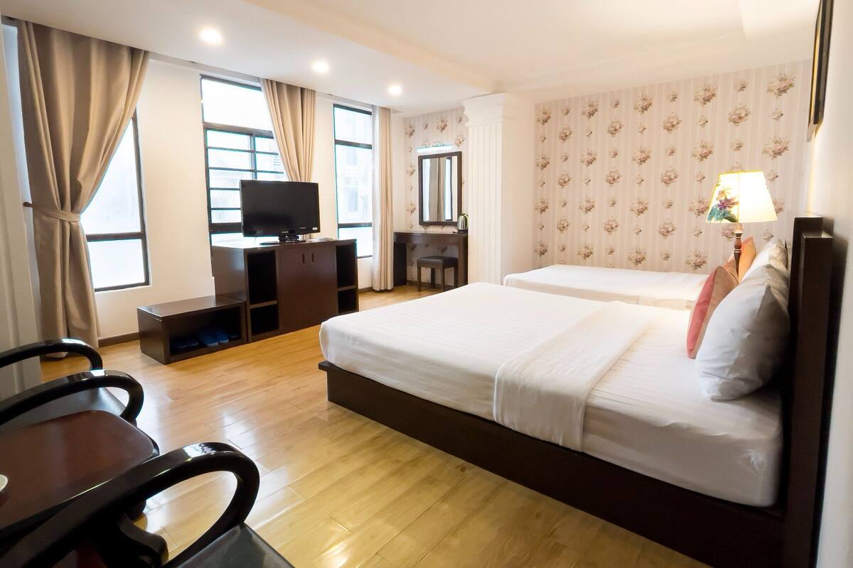 Une chambre d’hôtel avec deux lits, un bureau, une télévision et un miroir.