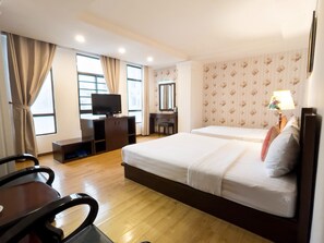 Een hotelkamer met twee bedden, een bureau, een televisie en een spiegel.
