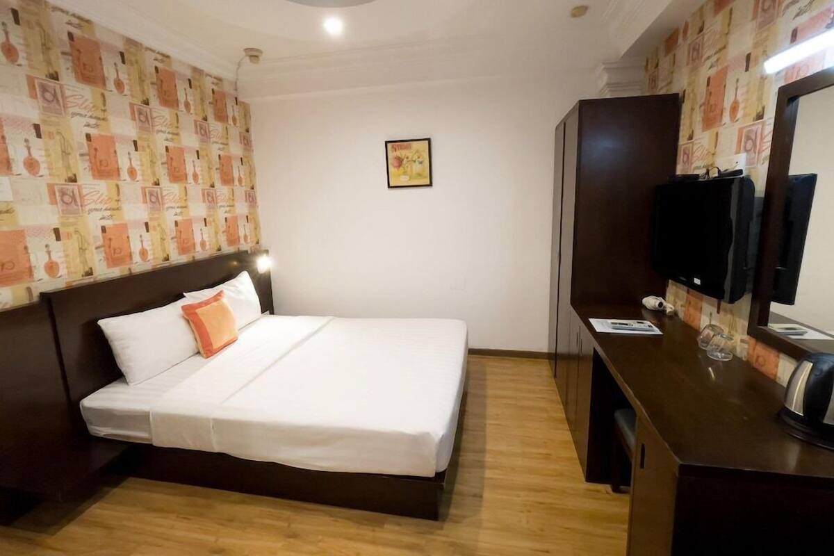 Une chambre d’hôtel avec un lit, un bureau avec une télévision et une armoire.