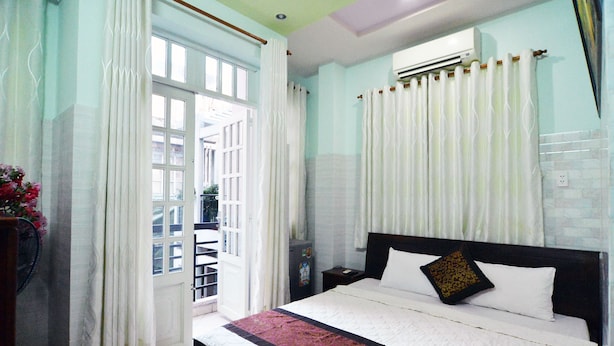 A hotel room with a bed, a nightstand, an air conditioner, and a window with curtains. - Lamenda Saigon Hotel (Ho Chi Minh City)