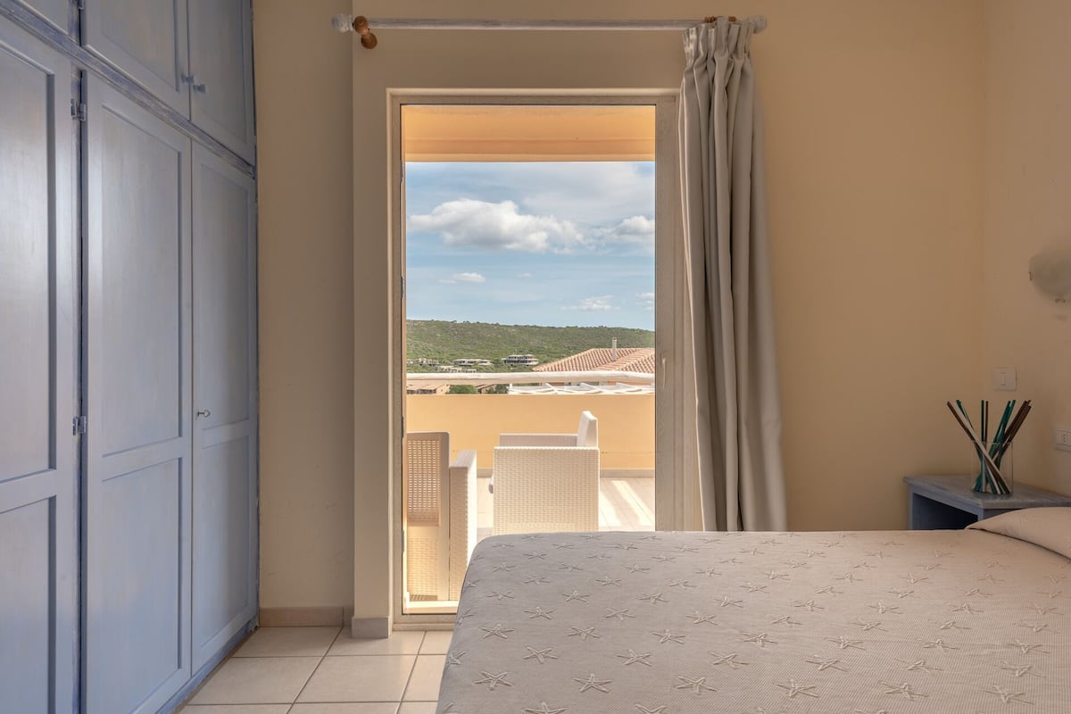 Une chambre avec un lit, une vue sur un balcon et une porte donnant sur l’extérieur.