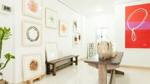 An art gallery with framed artworks on the walls, a wooden bench, and a table with decorative items. - The Passion (Chiang Mai)