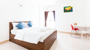 A hotel room with a wooden bed, white bedding, a desk, and a red chair. - The Passion (Chiang Mai)