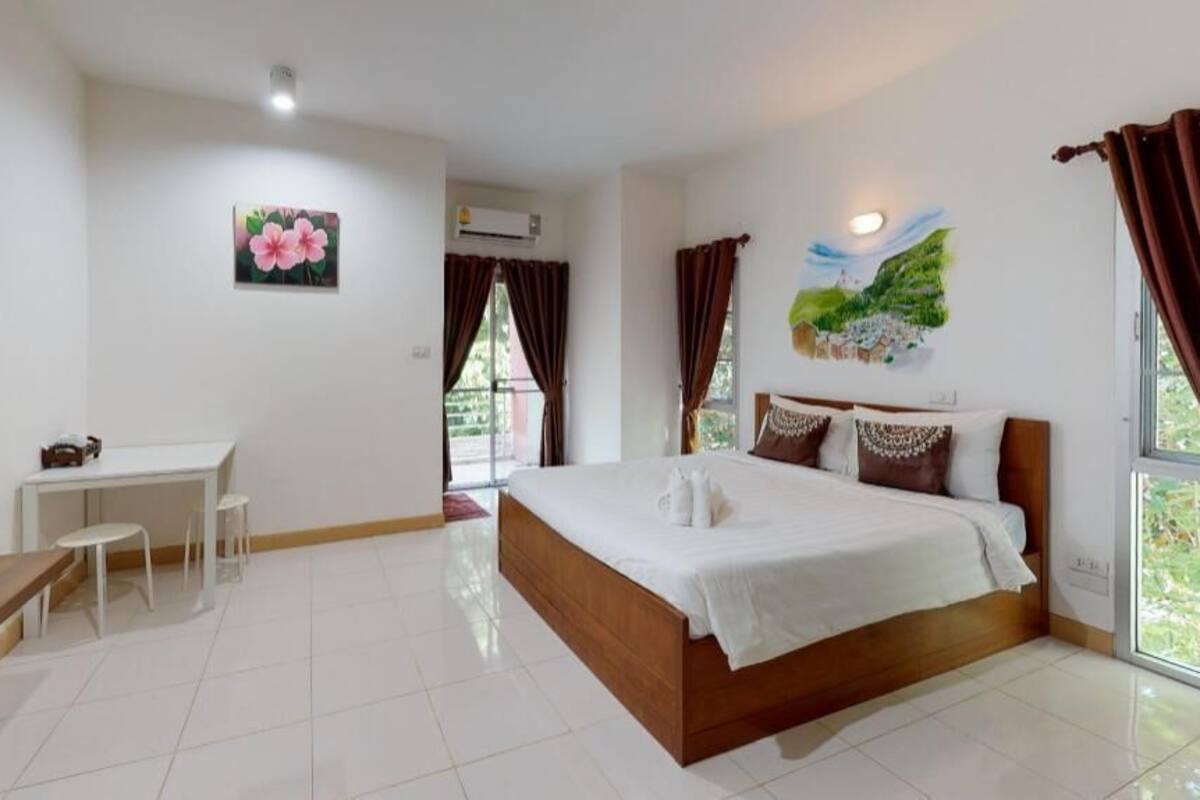 A bedroom with a bed, a desk, a chair, and a TV.