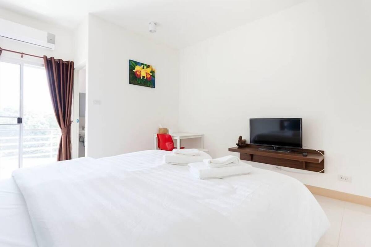 A hotel room with a large bed, a television, a small table, and a painting on the wall.