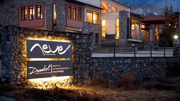 Ein modernes Hotel mit Steinsäulen und großen Fenstern, mit einem Schild für 'Neve' und 'Domotel'.