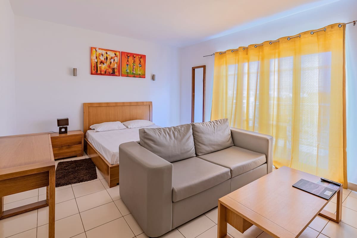 Une chambre à coucher avec un lit, un canapé, un bureau et une table de chevet.