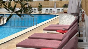 Una piscina con sillas de descanso y una pequeña mesa.