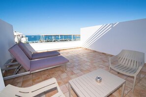 Terraza en la azotea con mesa de billar, sillones de descanso y vistas al mar.