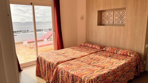 Een slaapkamer met een bed, uitzicht op het balkon en een decoratief wandpaneel.