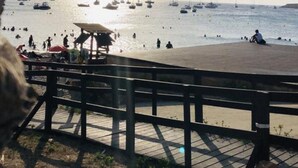 Escena costera con un muelle, barcos y gente.