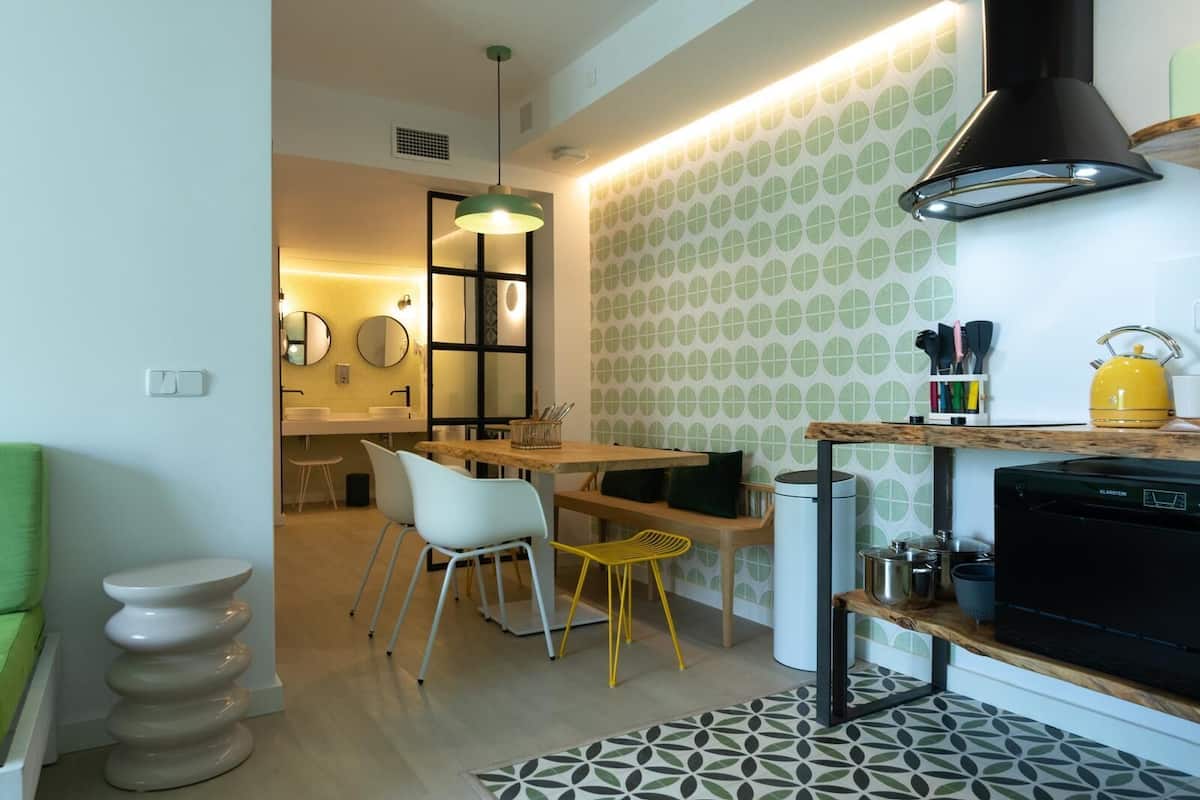 Una cocina moderna con comedor, un hervidor amarillo y una campana extractora negra.