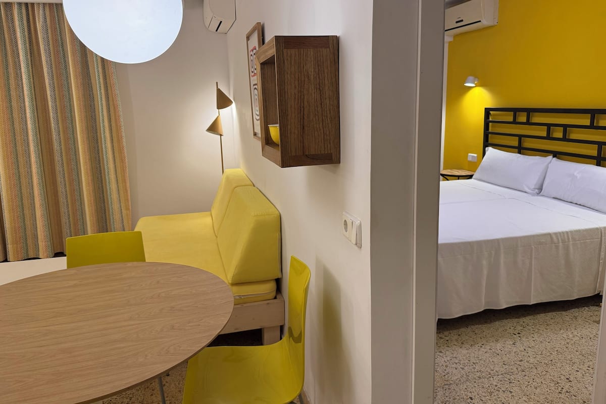 Una habitación de hotel con una cama, un escritorio con silla, una mesa redonda y una lámpara.