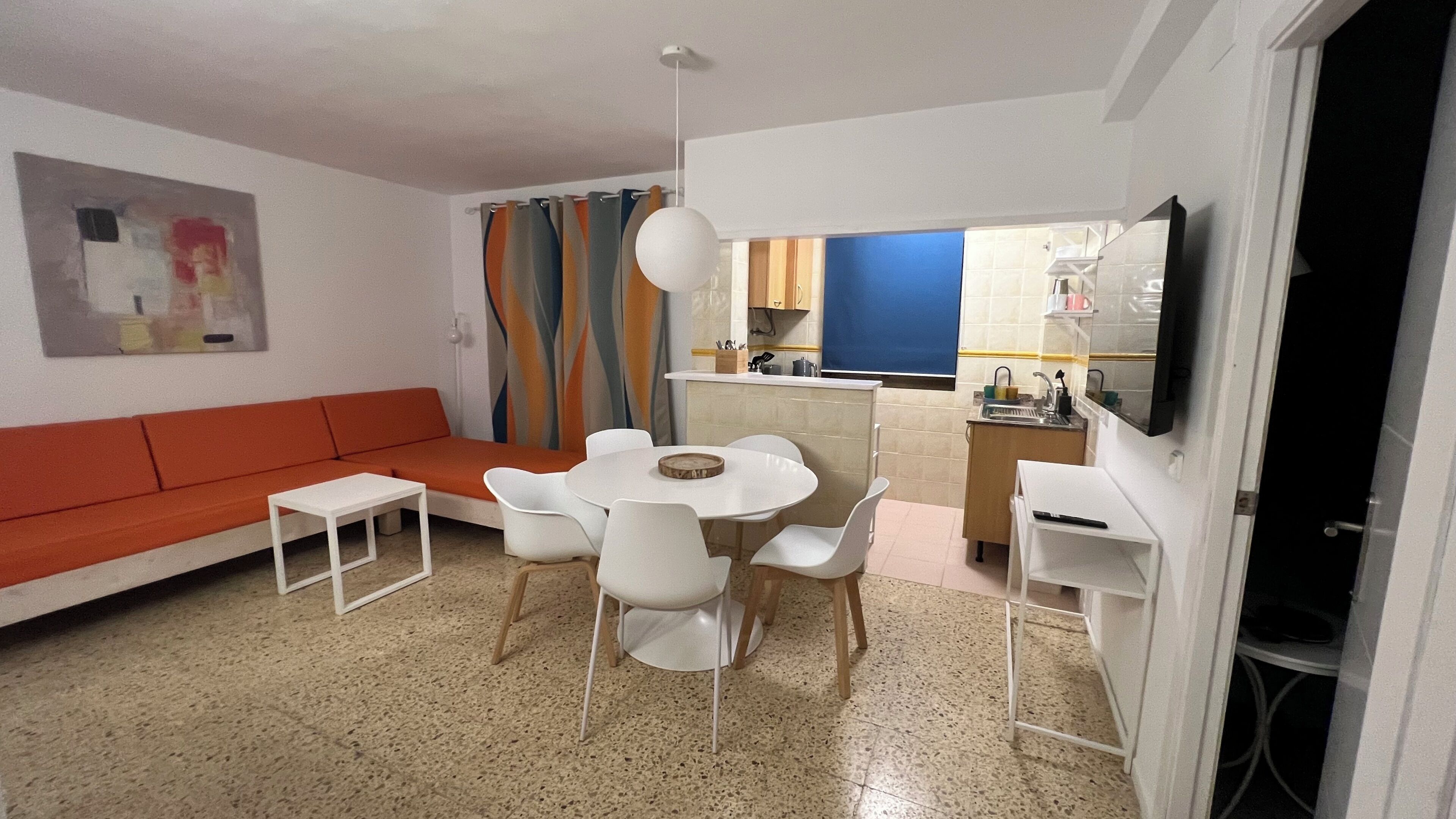 A living room with a sofa, dining table, chairs, and a TV.
