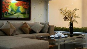 Un salon avec un canapé, une table basse, un tableau et un vase contenant des fleurs séchées.
